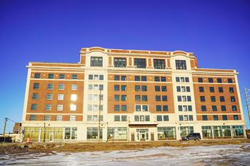 A large red brick building with a flat roof and a parking lot in front.